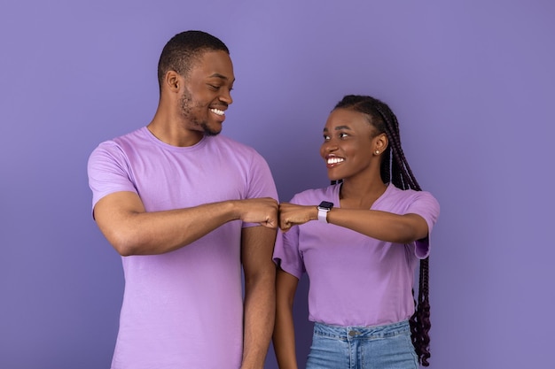 Retrato de feliz pareja negra celebrando ganar golpeando puños