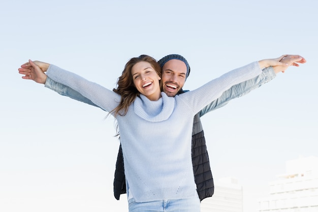 Retrato de la feliz pareja de pie con los brazos extendidos