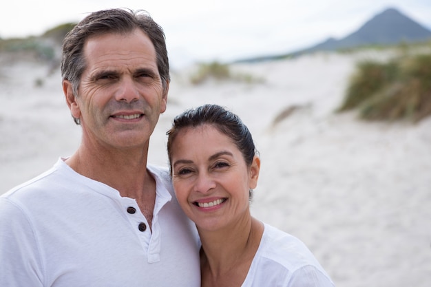 Retrato de la feliz pareja de pie en la playa