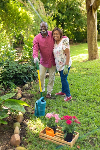 Retrato de feliz pareja senior afroamericana jardinería en el patio trasero