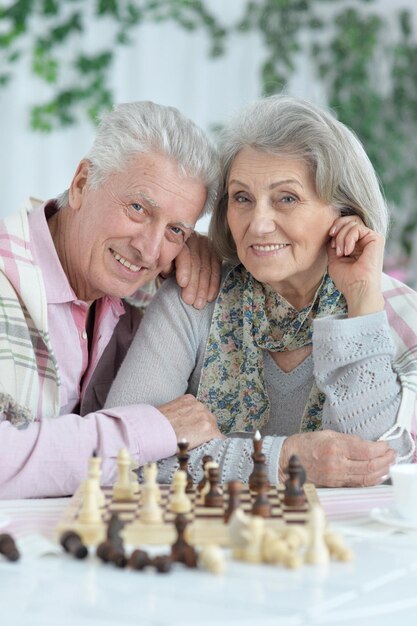 Retrato de feliz pareja senior jugando ajedrez juntos