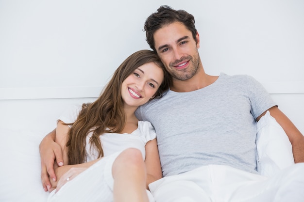 Retrato de la feliz pareja sentada en la cama