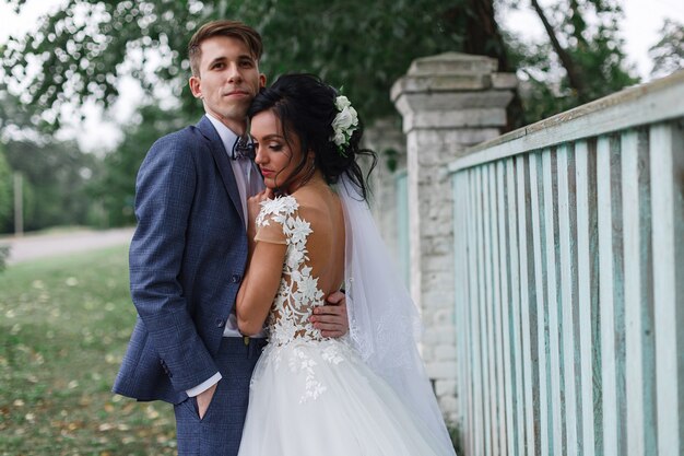 Retrato de la feliz pareja sonriente novias al aire libre. recién casados en un paseo en el parque verde de la primavera. los recién casados emocionales se besan y abrazan durante un paseo de bodas. día de la boda.