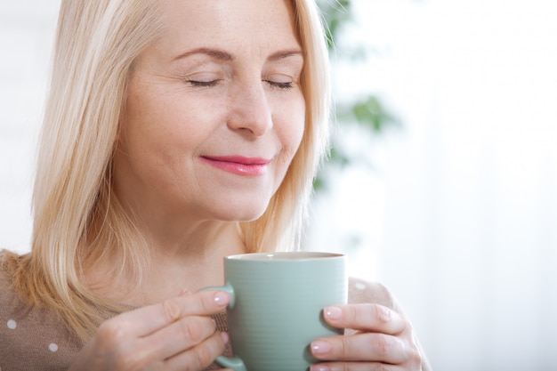 Retrato de feliz rubia con taza en manos