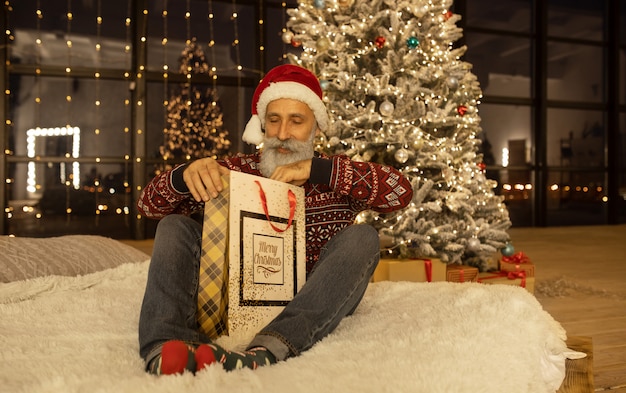 Retrato de feliz Santa Claus en su habitación en casa cerca del árbol de Navidad.