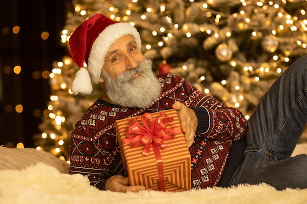 Retrato de feliz Santa Claus en su habitación en casa cerca del árbol de Navidad.