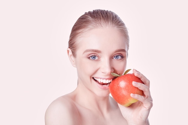 Retrato de feliz sonriente joven bella mujer comiendo manzana roja sobre fondo blanco.