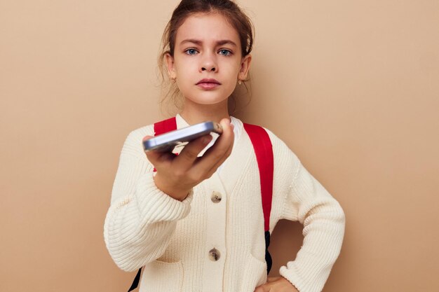 Retrato de feliz sonriente niño niña colegiala mochila teléfono en mano infancia inalterada