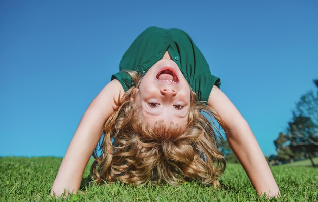 retrato, de, un, feliz, sonriente, niño, niño, boca abajo, en, campo de hierba, niño que ríe, niño, expresivo, facial