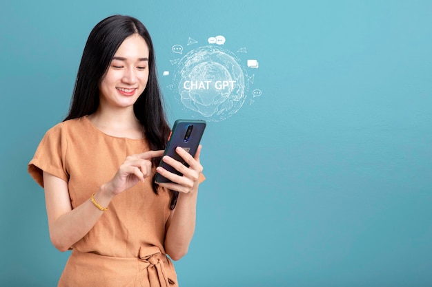 Foto retrato feliz sorridente jovem asiática usando smartphone isolado em fundo azul