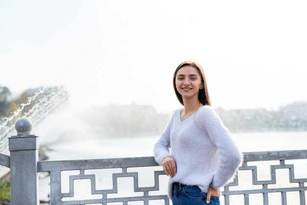 Retrato femenino. Hermosa mujer en ropa casual posando a orillas del lago con fuente