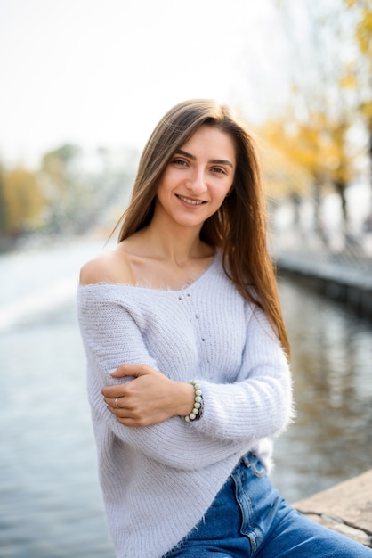 Retrato femenino. Hermosa mujer en ropa casual posando a orillas del lago con fuente