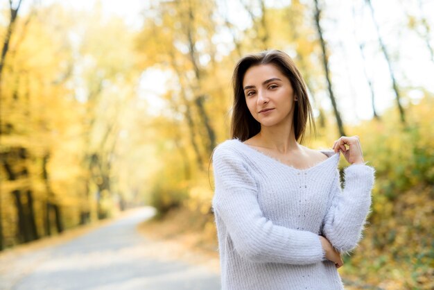 Retrato femenino. Mujer joven en ropa casual posando en el bosque de otoño con hojas amarillas