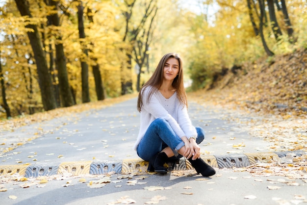 Retrato femenino. Mujer joven en ropa casual posando en el bosque de otoño con hojas amarillas