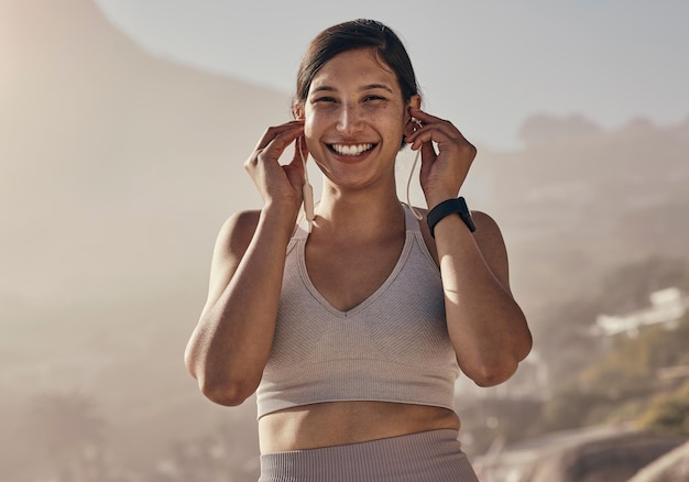 Retrato fitness e música para mulher na natureza para treinamento de corrida e cardio em fundo desfocado Rosto feliz e rádio para garota ao ar livre para exercícios de bem-estar e motivação com faixa de podcast