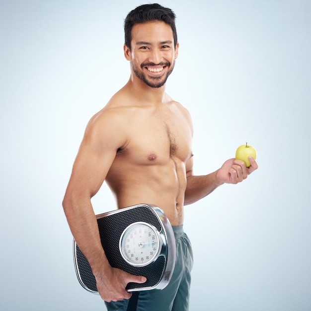 Foto retrato de fitness o hombre con una manzana o una báscula en el estudio para motivar a perder peso con una dieta saludable nutrición de frutas o modelo masculino con metas corporales objetivo de entrenamiento o sonrisa feliz con maqueta