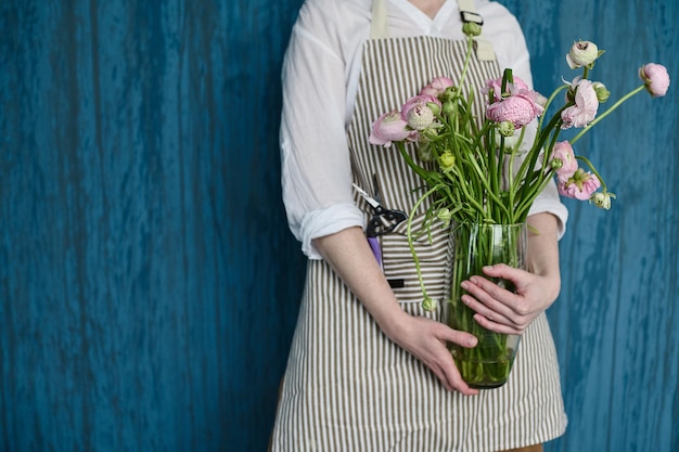 Retrato de una floristería hermosa joven sobre un fondo azul con un ramo en sus manos