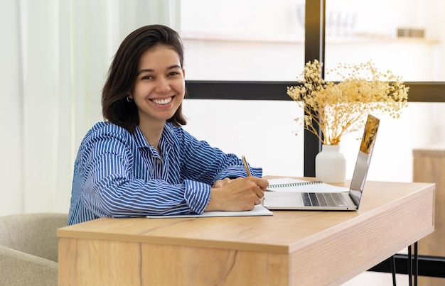 Retrato de foto de cerca de una hermosa mujer latinoamericana con cabello rizado mujer de negocios dentro de un edificio de oficinas sonriendo y mirando a la cámara
