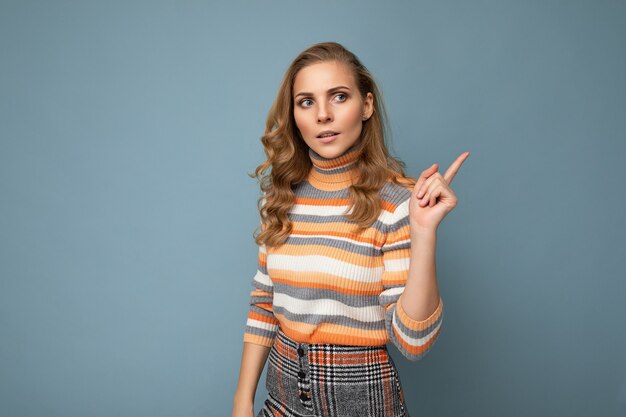 Retrato de la foto de la joven y bella mujer rubia seria concentrada vistiendo elegantes colores