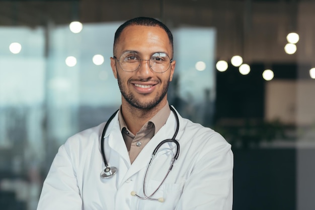 Retrato fotográfico aproximado de um jovem médico hispânico masculino bonito parado no salão de vidro do