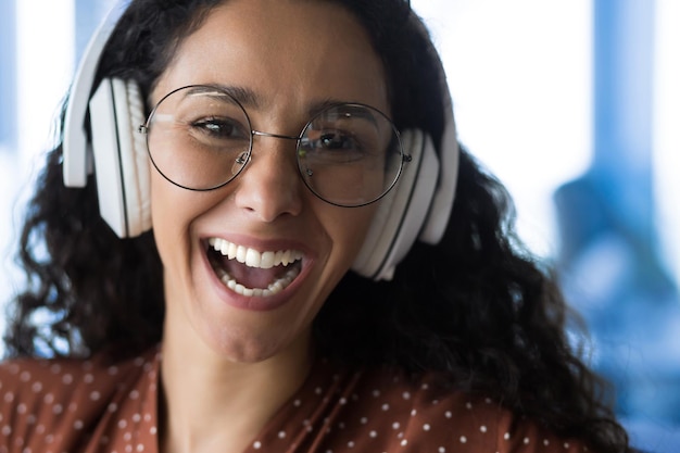 Retrato fotográfico aproximado de uma mulher feliz usando óculos sorrindo e feliz ouvindo música em branco