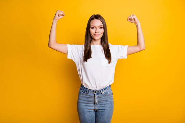 Retrato fotográfico de chica en forma mostrando músculos aislados sobre fondo de color amarillo brillante