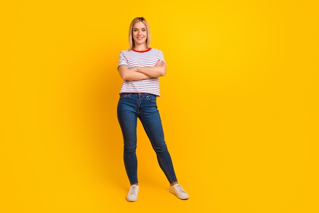 Retrato fotográfico de comprimento total de mulher em pé com os braços cruzados isolados em fundo colorido vívido