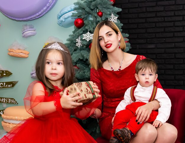 Retrato fotográfico familiar Mamá y sus dos hijos vestidos de rojo celebran el año nuevo de Chistmas