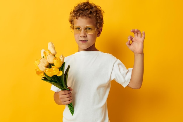 Retrato fotográfico menino encaracolado com um buquê de flores amarelas cor de fundo inalterada