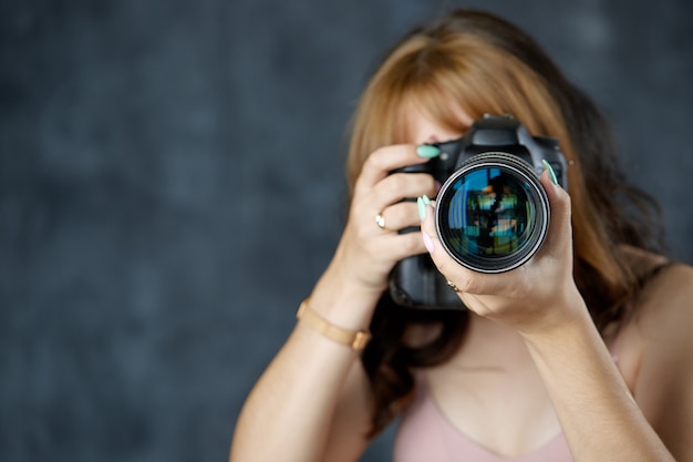 Retrato de un fotógrafo que cubre su rostro con la cámara Niña con una cámara profesional en sus manos Enfoque selectivo