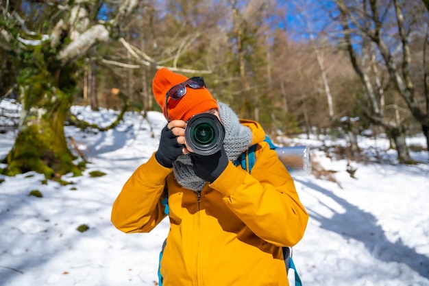 Retrato de un fotógrafo tomando fotos de invierno en las montañas con nieve haciendo un trekking con una mochila