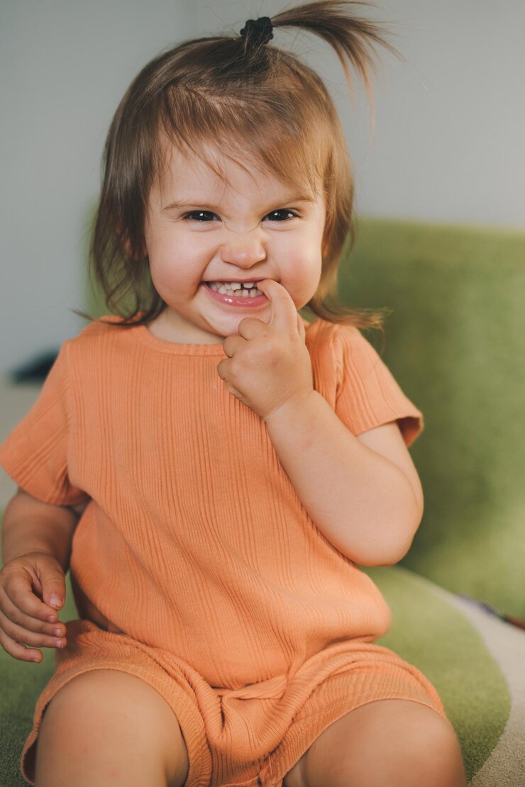 Foto retrato frontal de uma adorável menina sorrindo enquanto tocava seu dente de leite com o dedo infância familiar feliz menina sorridente casa pequena