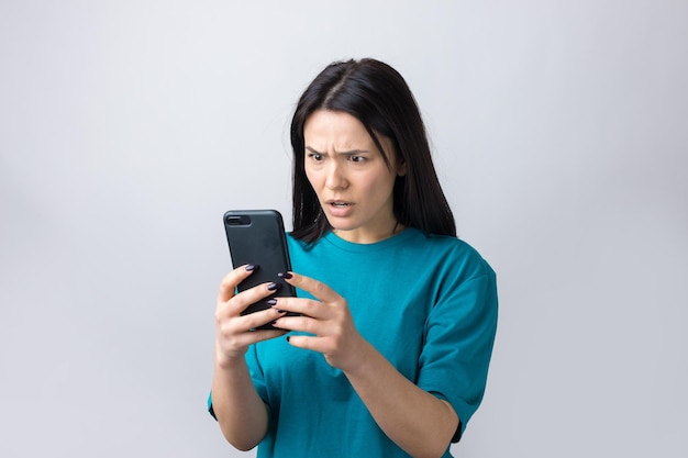 Foto retrato frontal de uma jovem sorridente usando telefone celular contra fundo cinza