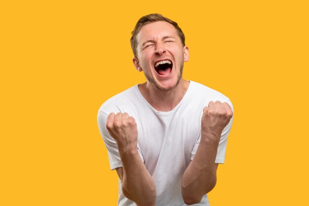 Retrato de ganador. Gesto de éxito. Hombre emocionado celebrando la gloria gritando aislado sobre fondo naranja.