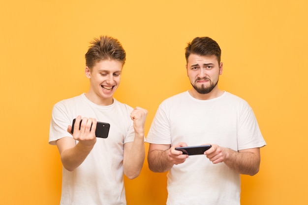 Retrato de ganador y perdedor, dos amigos jugando juegos móviles