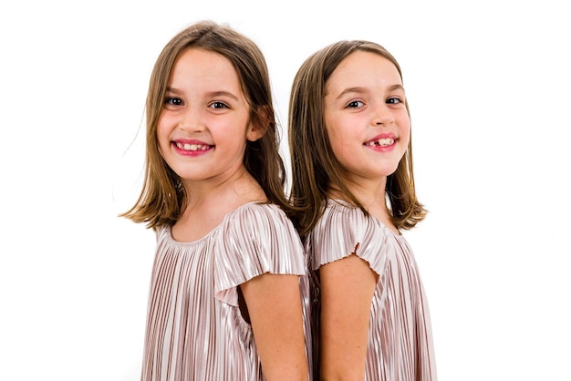Foto retrato de gemelos sonrientes de espaldas contra un fondo blanco