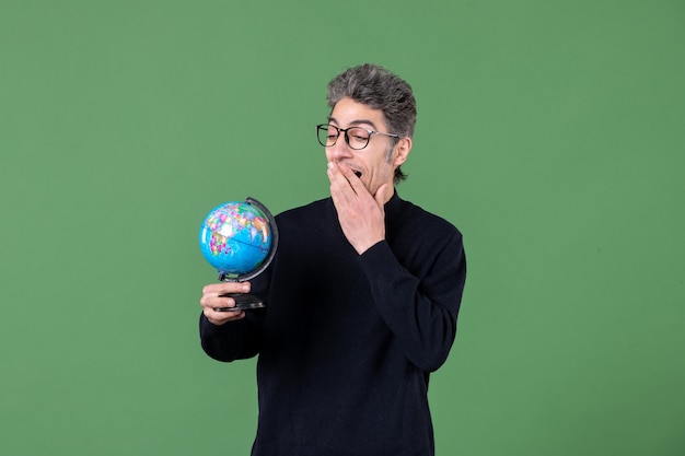 retrato de genio hombre sosteniendo pequeño globo terráqueo foto de estudio fondo verde maestro naturaleza espacio planetas