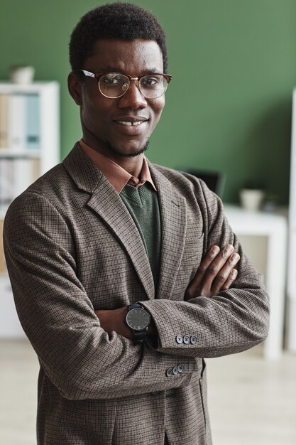 Retrato de gerente africano en traje de moda de pie con los brazos cruzados y sonriendo