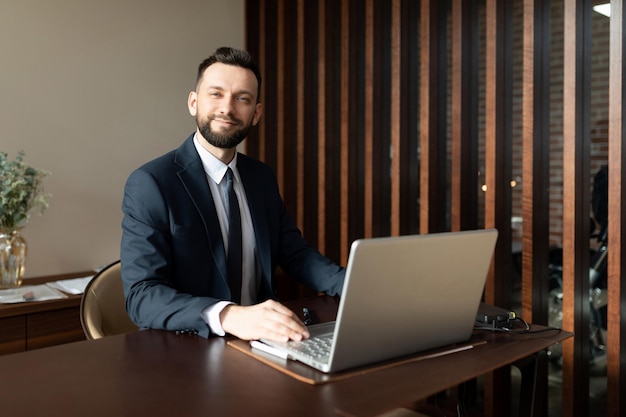 Retrato de un gerente de seguros educado en una oficina de moda en una computadora portátil