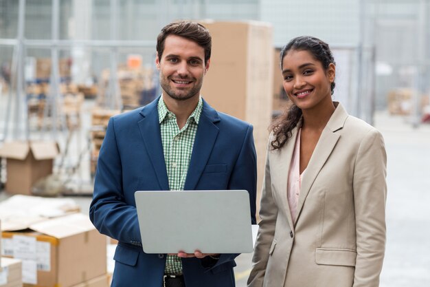 Foto retrato de gerentes felices posando y sonriendo con una computadora portátil