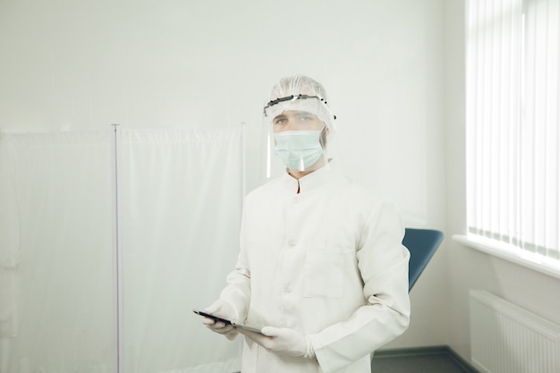 Retrato de un ginecólogo con traje de protección que se prepara para recibir a los pacientes durante la cuarentena del coronavirus. Médico con equipo de protección personal durante una pandemia.