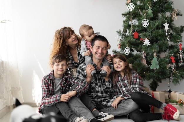 Retrato de una gran familia caucásica completa con tres hijos en Navidad con regalos sentados en el suelo de la casa en la sala de estar