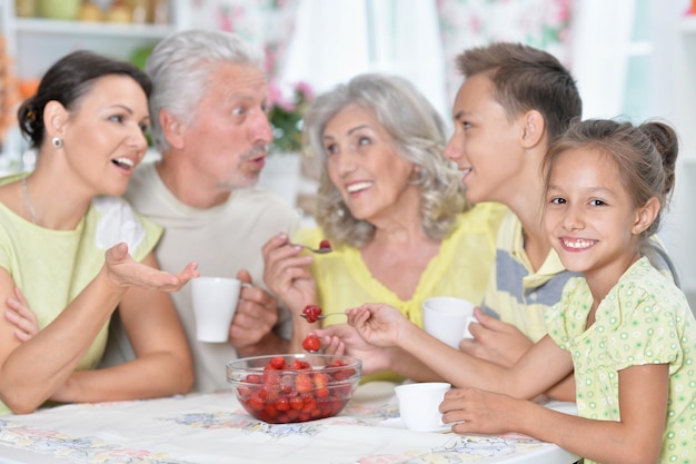 Retrato de una gran familia feliz comiendo fresas frescas en la cocina