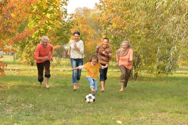 Retrato de una gran familia feliz jugando al fútbol en el parque