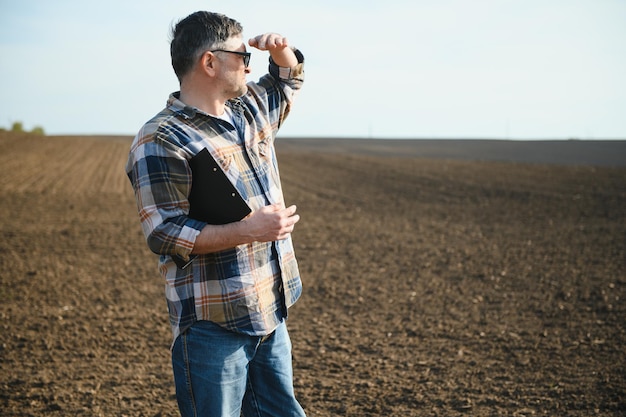 Retrato de granjero senior con gafas en el campo