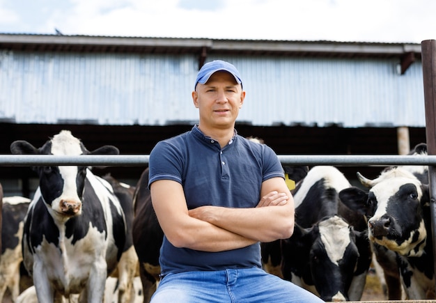 Retrato de un granjero entre vacas en una granja