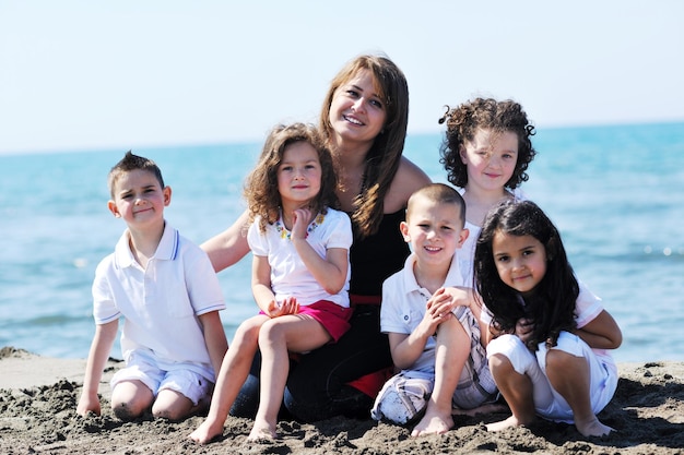 retrato grupal de niños felices con una joven maestra en la playa