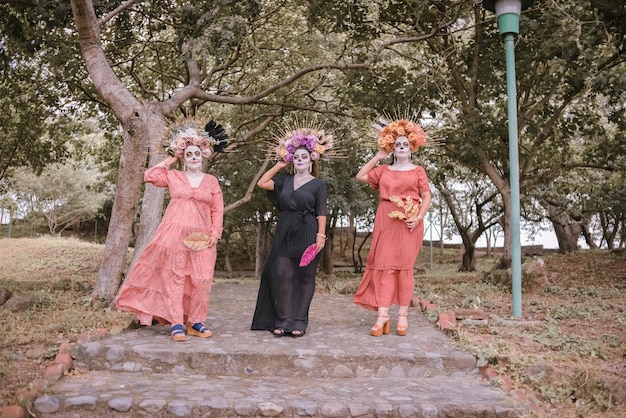 Retrato grupal de tres mujeres con el maquillaje de las catrinas. Maquillaje para dia de muertos.