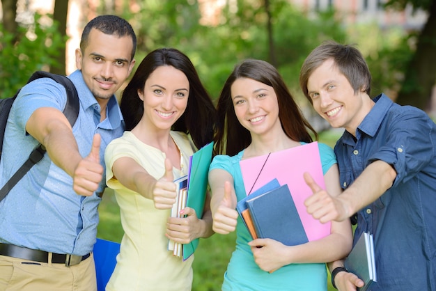 Retrato de grupo de cuatro estudiantes alegres sonrientes.