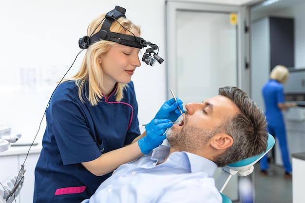 Retrato de grupo de dos personas mujer dentista haciendo tratamiento en clínica moderna para hombre Fotografía de concepto médico en interiores para odontología Médico de consultorio dental que trabaja en clínica con paciente